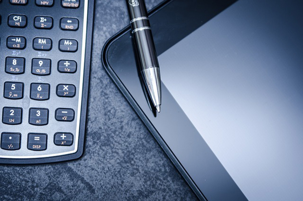 Calculator, tablet and pen sitting on top of tablet